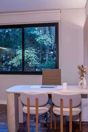 Sala de consulta com mesa clara e vista para as árvores
